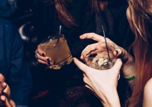 People are holding drinks and engaging in lively conversation at a social gathering or party.