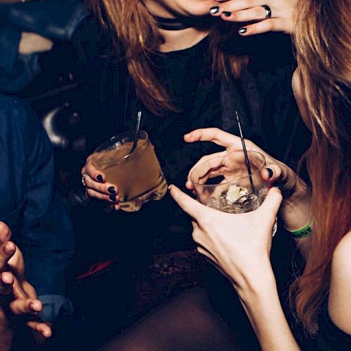 People are holding drinks and engaging in lively conversation at a social gathering or party.