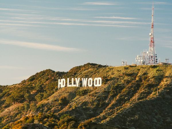 This image shows the iconic "HOLLYWOOD" sign on the hills with a radio tower nearby, set against a clear sky at dusk.